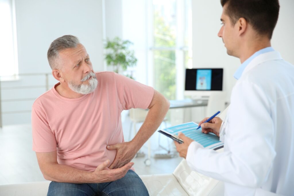 pacient-cu-barba-alba-indicand-zona-in-care-simte-dueri-sau-disconfort-in-timpul-unei-consultatii-medicale