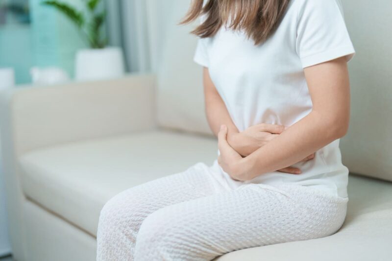 femeie imbracata in alb cu dureri menstruale dismenoree
